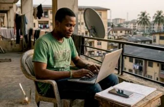 Young Nigerian using laptop on balcony for forum