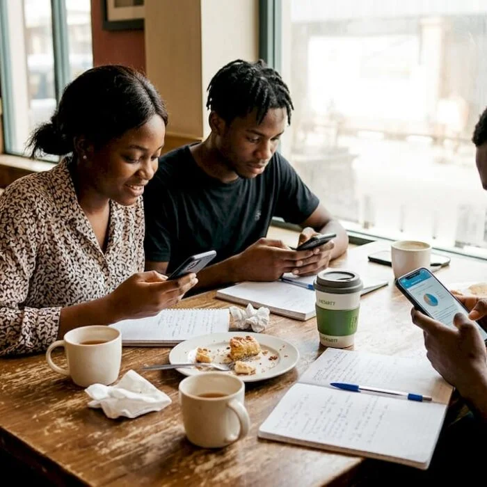 Nigerian students using smartphones at café table