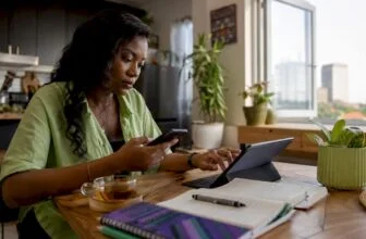 Nigerian woman verifying news on smartphone and laptop