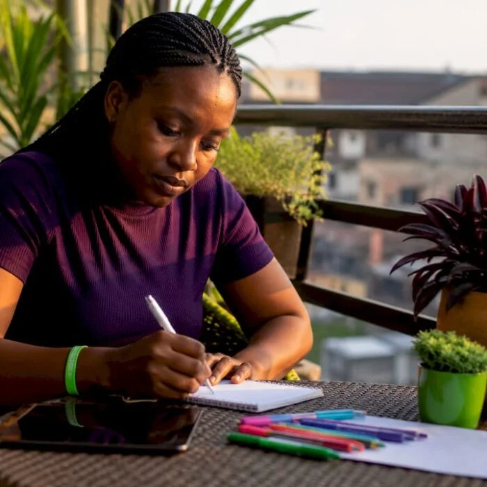 Nigerian woman writing citizen feedback at home desk