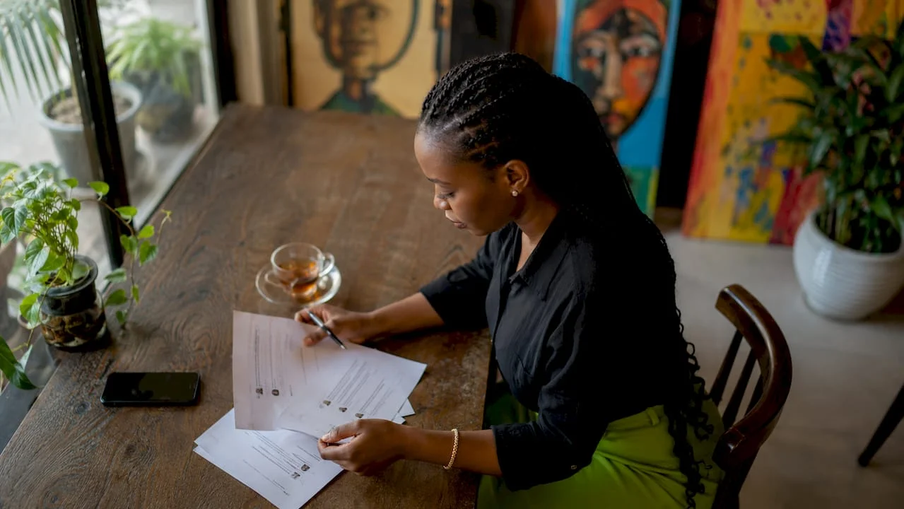 Why Moderate Comments: A Guide for Nigerian Communities 1 Nigerian woman moderating printed comments at desk