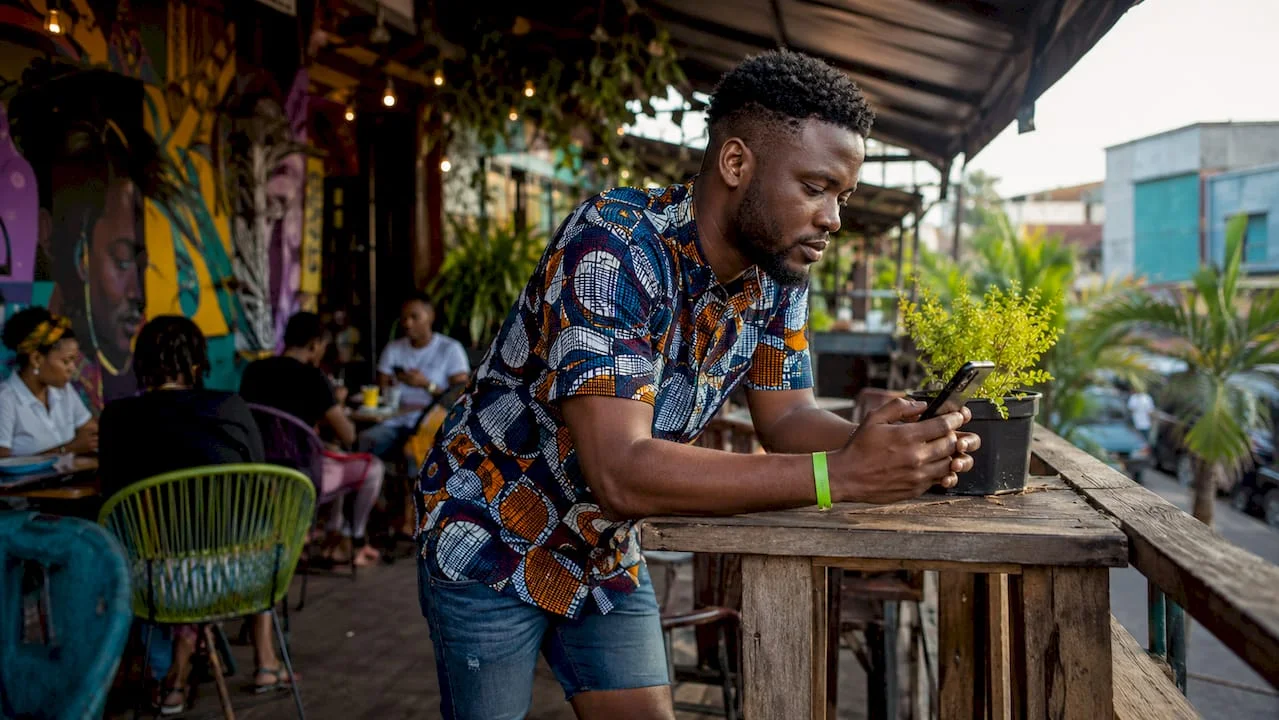 How to Access Local Entertainment Updates in Nigeria 1 Man checking entertainment updates on phone at market