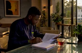 Young Nigerian adult reading political commentary at home