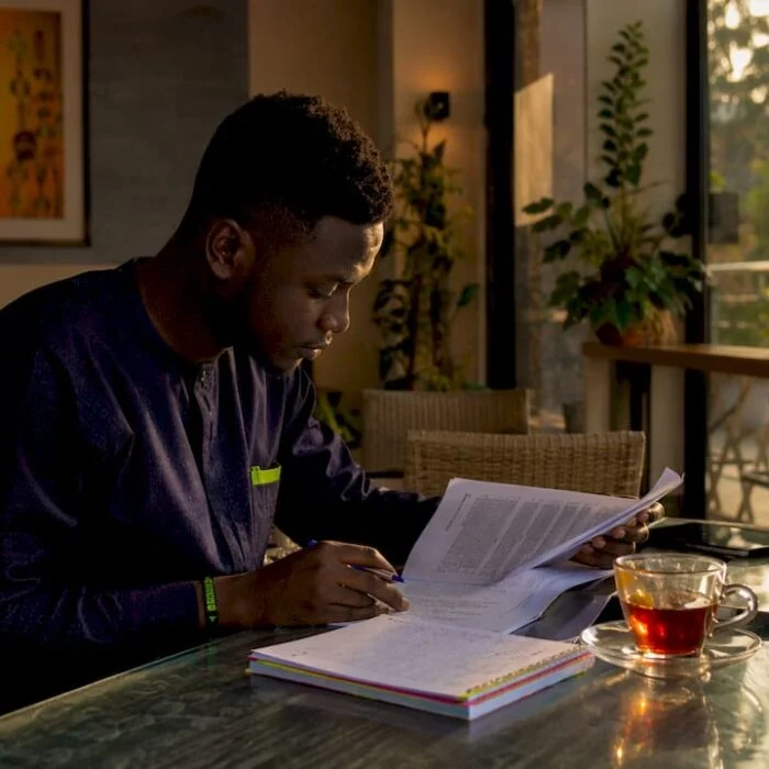 Young Nigerian adult reading political commentary at home