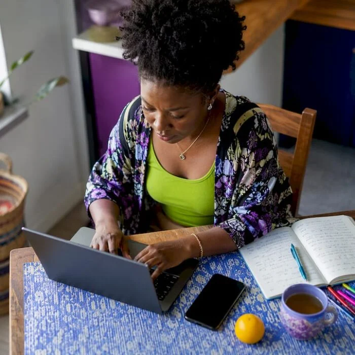 Nigerian woman typing blog setup at home office desk