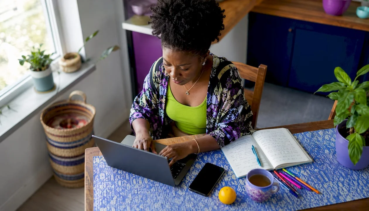 Nigerian woman typing blog setup at home office desk