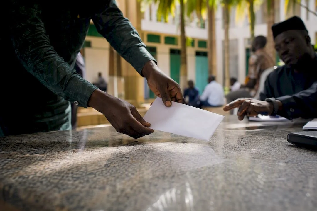 What Is Nigeria's National Assembly and Who Runs It? 3 Hands submitting documents at government counter