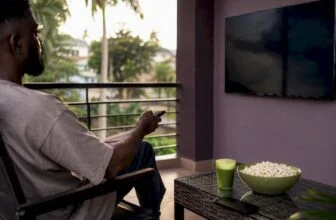 Person holding remote to TV for BBNaija viewing