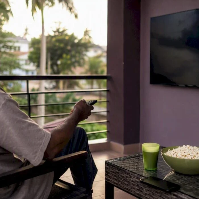 Person holding remote to TV for BBNaija viewing
