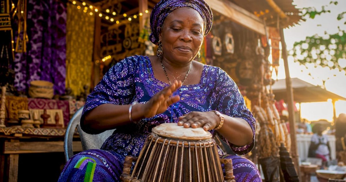 The Role of Entertainment in Nigerian Culture, Identity and the Economy (2026) 1 Nigerian woman playing traditional drum outdoors