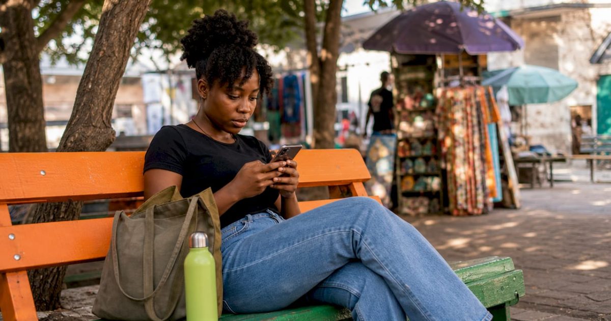 Nigerian woman using smartphone outdoors in market