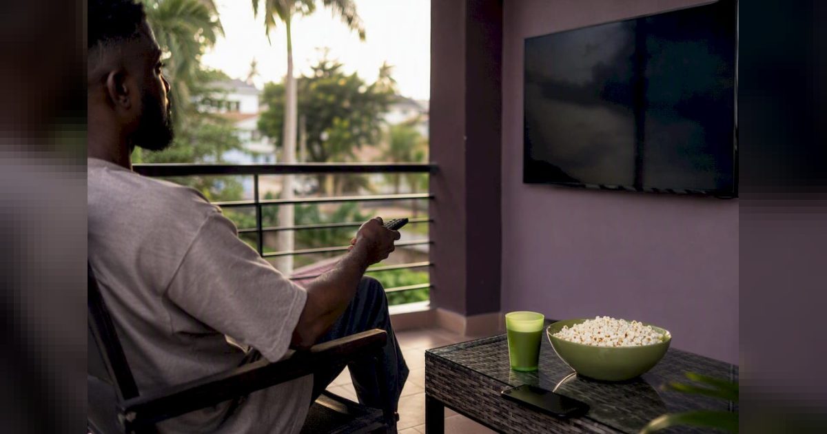 BBNaija Season 11: Premiere, N160m Prize, How to Watch and How the Show Works 1 Person holding remote to TV for BBNaija viewing